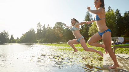 Chicas en bikini saltando al lago