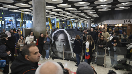 Un grupo de personas sostiene una pancarta con la foto de Rocío San Miguel, una de las liberadas en Venezuela, en el Aeropuerto Adolfo Suárez Madrid Barajas