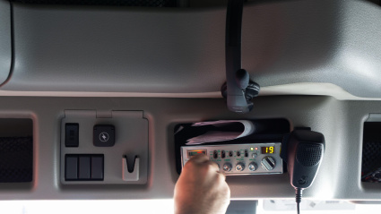 Una persona está ajustando los controles dentro de la cabina de un camión mientras está estacionado en un área urbana.