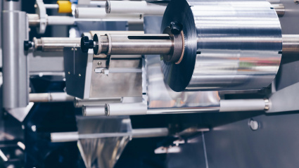 Rollo de papel de aluminio para envasado de alimentos en la envasadora automática de una fábrica de productos alimenticios. Concepto industrial y tecnológico.
