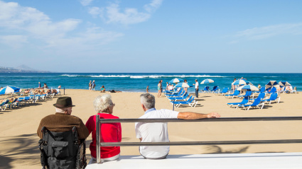 Jubilado en silla de ruedas mirando hacia la playa en España