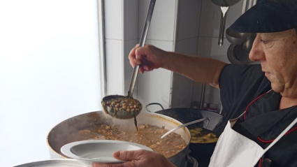 Una cocinera sirviendo una ración de garbanzos con bacalao