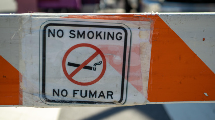 Cartel de no fumar pegado en una valla de obra