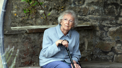 Jubilada sola sentada en un banco descansando