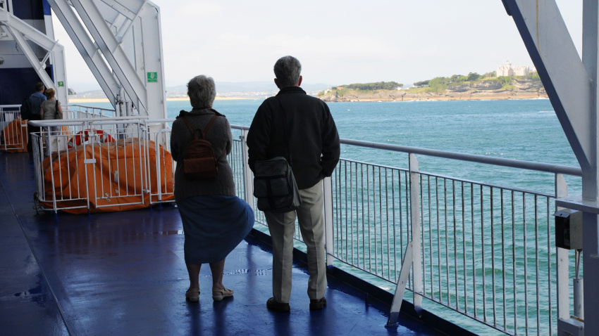Vista trasera de una pareja de ancianos en cubierta mirando hacia tierra, a bordo del ferry de cruceros, al entrar en Santander