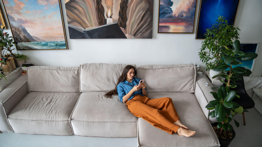 Una mujer tirada en el sofá con el móvil