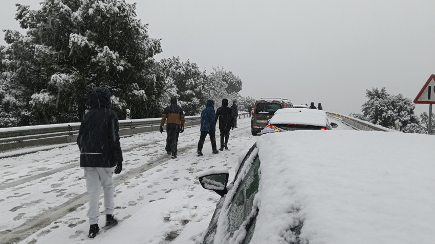 Una persona camina junto a varios vehículos en la carretera M-519 a la altura de Galapagar, en Madrid