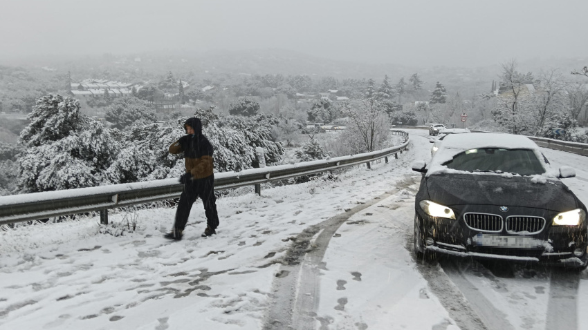 Una persona camina junto a varios vehículos en la carretera M-519 a la altura de Galapagar