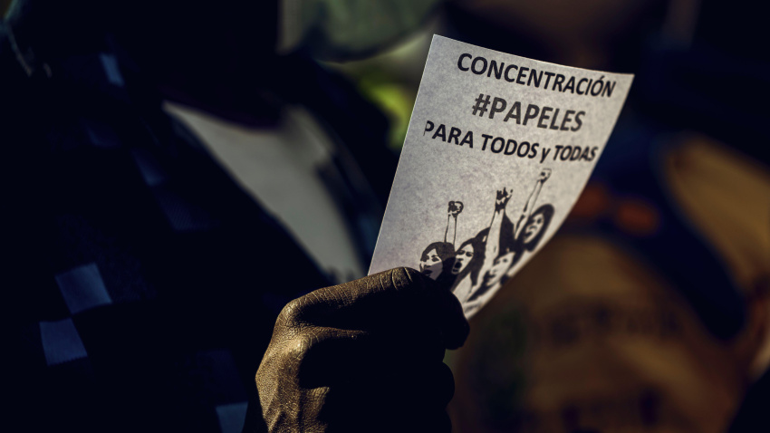 Una trabajadora doméstica migrante protesta por documentos y regulaciones sosteniendo una pancarta.