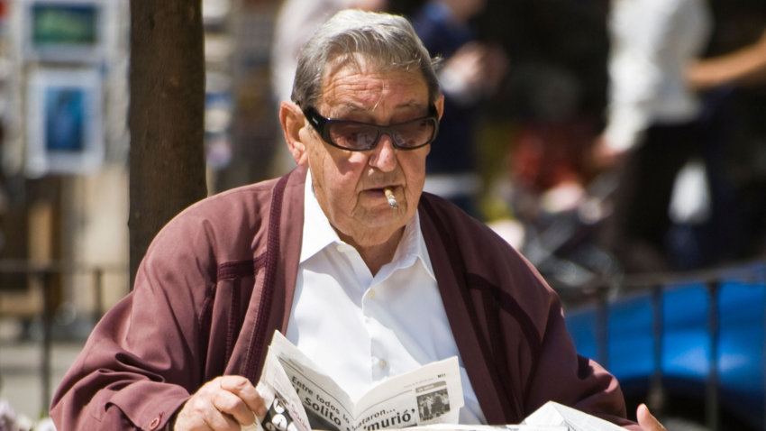 Jubilado leyendo un periódico en un banco del parque, Valencia