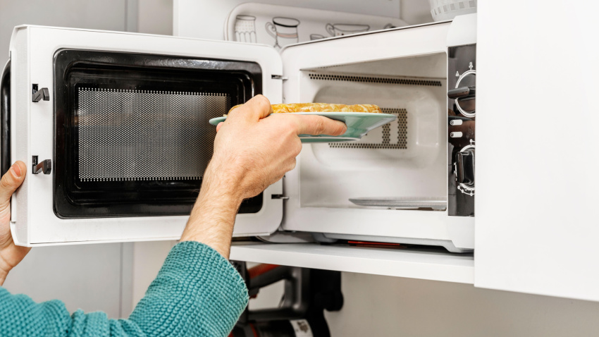 Una mujer mete una tortilla de patata en un microondas