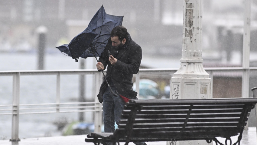 Un hombre se intenta proteger con el paraguas de la lluvia en el puerto deportivo de Gijón
