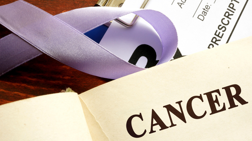 Cáncer escrito en una página y cinta rosa de concienciación.
