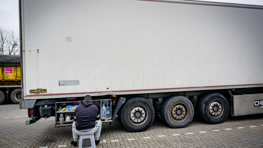Un conductor de camión está comiendo y descansando en un estacionamiento de camiones a lo largo de la carretera.