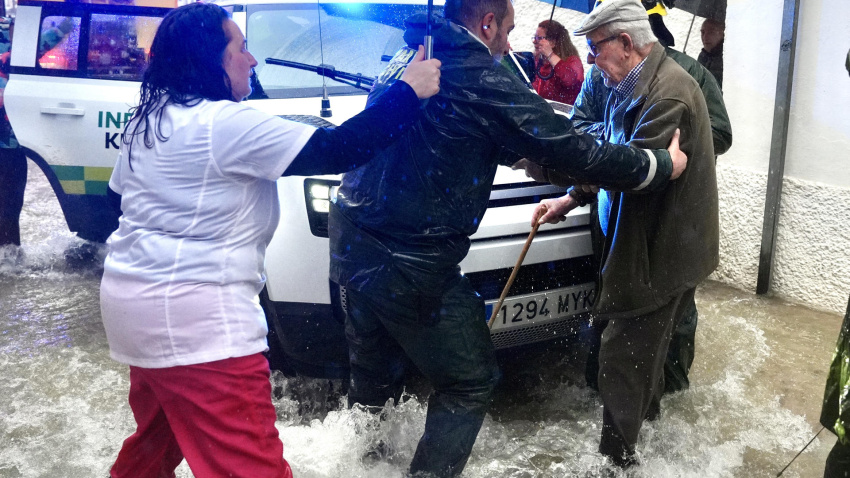 Vecinos de Grazalema ayudan a una persona mayor en una calle inundada debido a las intensas lluvias