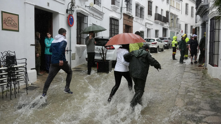 Vecinos de Grazalema corren por una calle inundada debido a las intensas lluvias