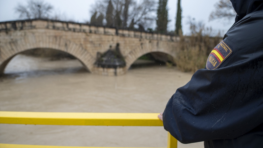 Agentes de la Policía Nacional vigila la crecida del río Guadalbullón a su paso por la localidad