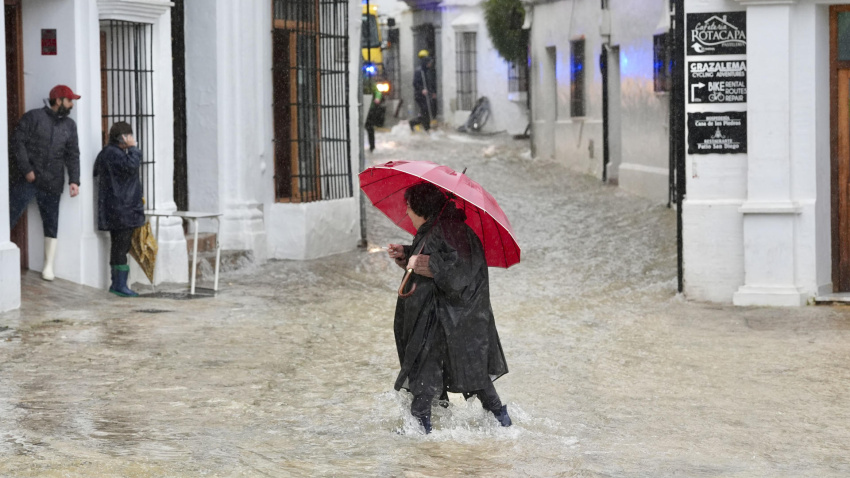 Una vecina de Grazalema (Cádiz) camina por una calle inundada debido a las intensas lluvias que se registran en la localidad gaditana