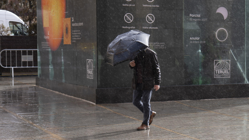 Un hombre camina bajo la lluvia en el centro de Teruel