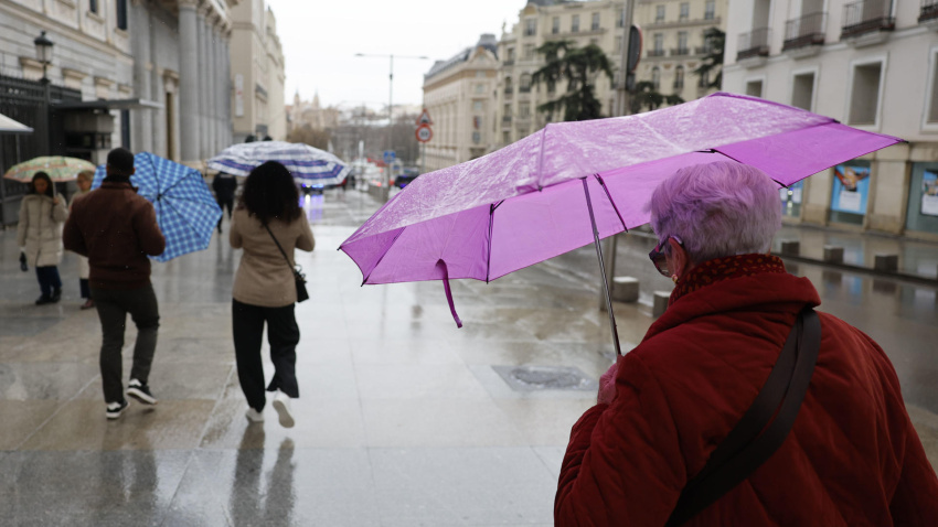 Varias personas se protegen de la lluvia en Madrid