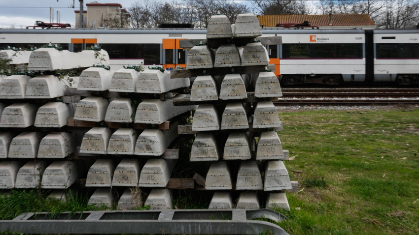 Vista de un tren parado junto a un cargamento de traviesas en la línea R1 de Rodalies