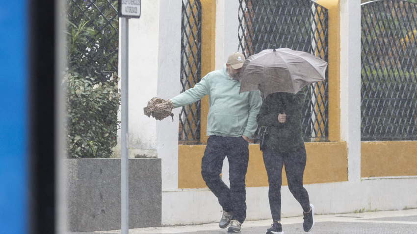 Una mujer se protege del viento y la lluvia en Huelva