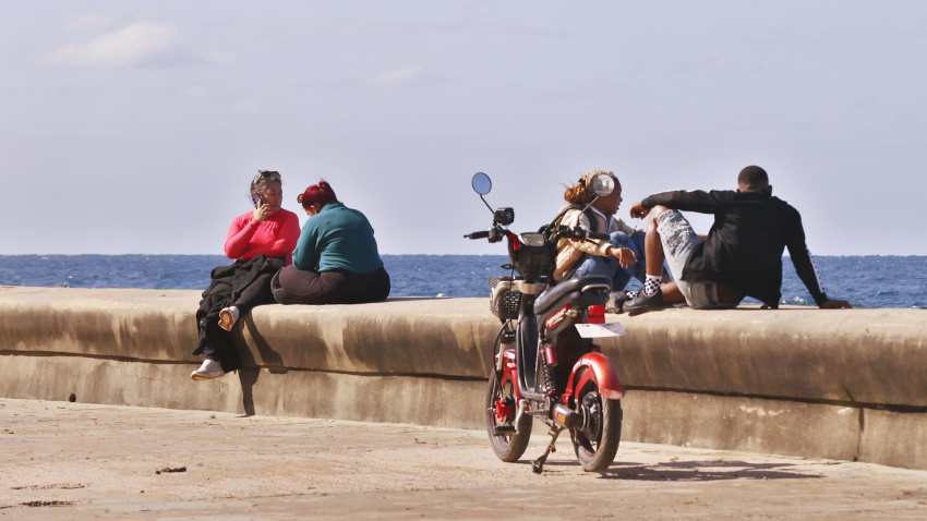 Fotografía que muestra a personas observando el mar en el Malecón de La Habana (Cuba)