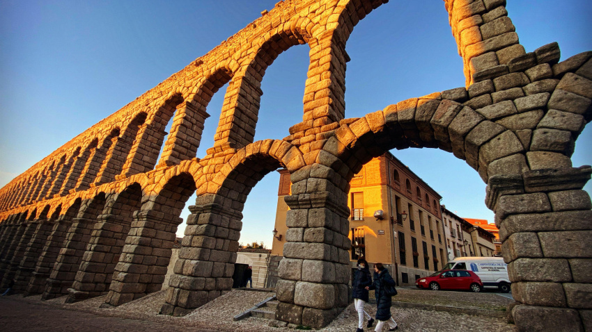 Dos personas caminan bajo el Acueducto romano de Segovia