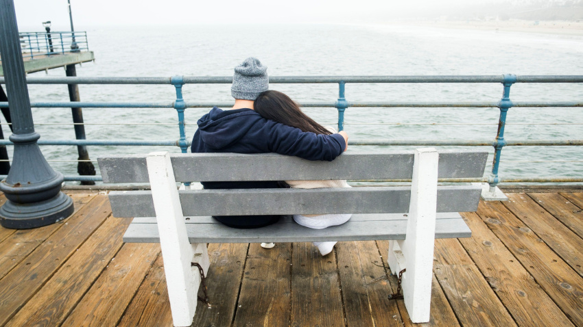 Pareja enamorada sentada en un banco disfrutando de las vistas