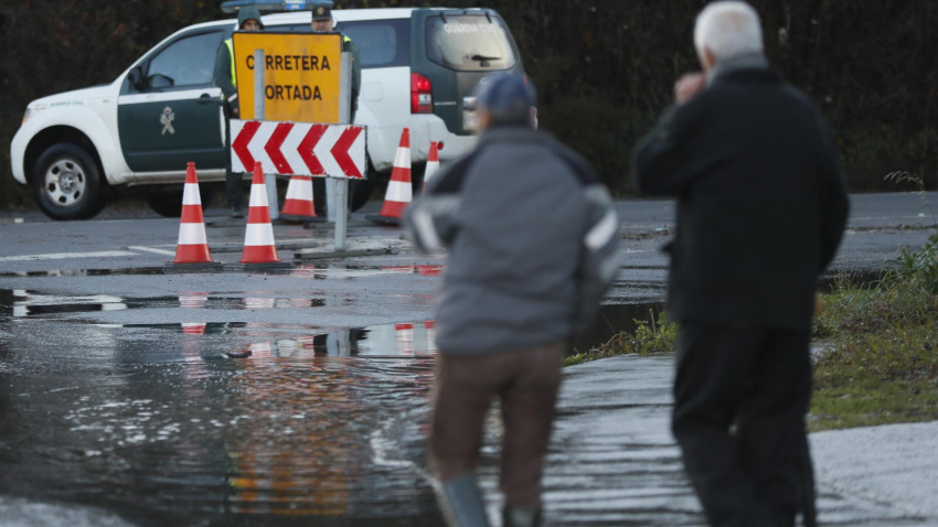 Dos hombres y agentes de la Guardia Civil observan el estado de una carretera en Lugo