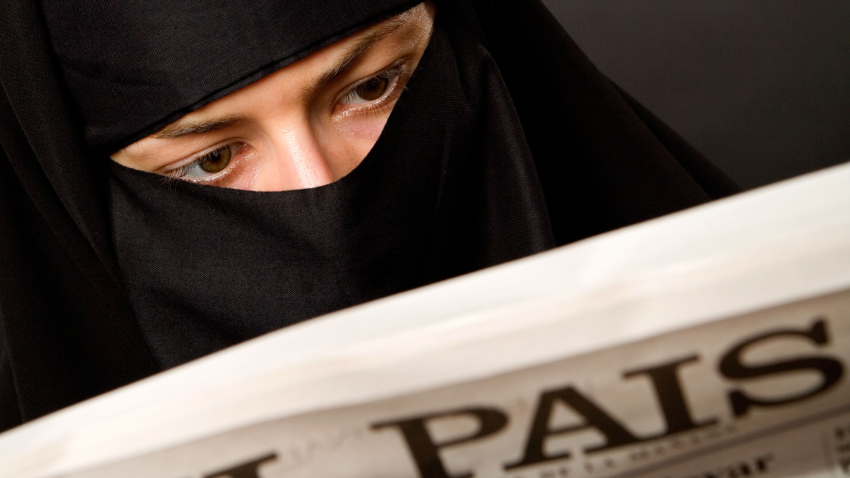 Una mujer musulmana con hiyab burka lee el periódico español El País