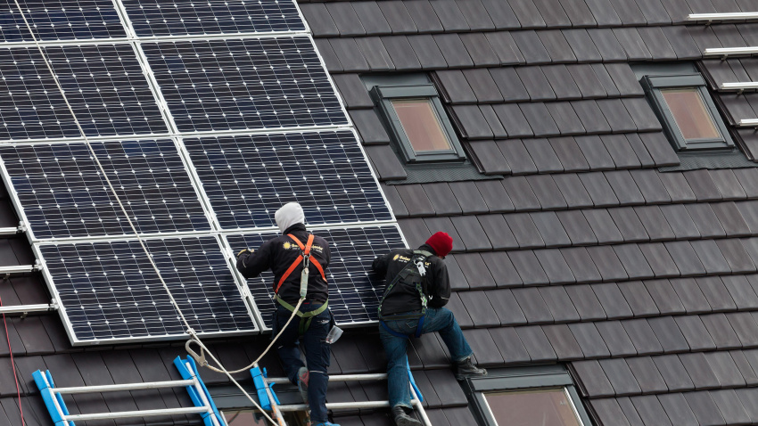 Trabajadores de la construcción instalando paneles solares en los tejados de casas