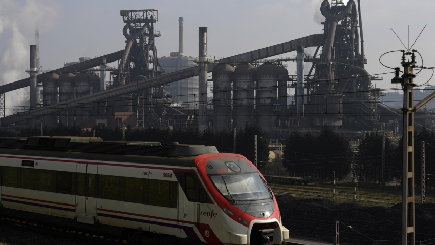 Un tren circula por delante de la fábrica de ArcelorMittal en Gijón