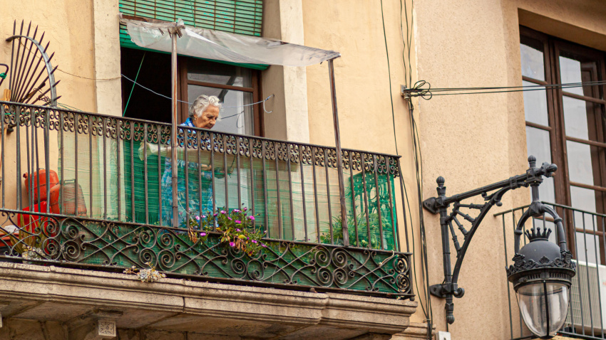 Una jubilada con cabello gris en el pequeño balcón de su apartamento.