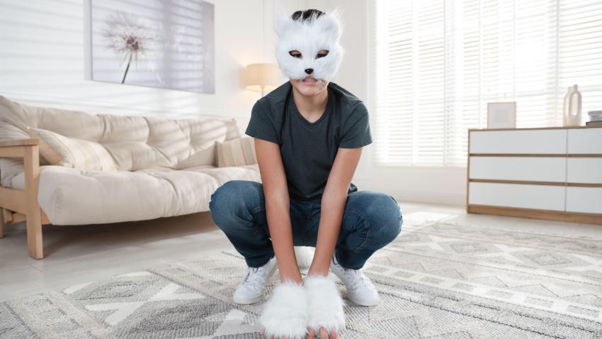 Quadrobics. Persona con máscara de gato y guantes en casa siguiendo la moda de los therians