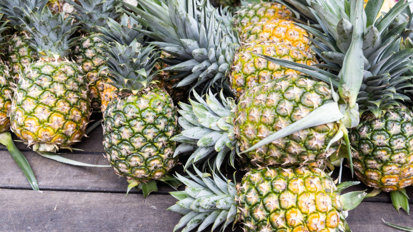 Montón de piña orgánica recién cosechada sobre superficie de madera