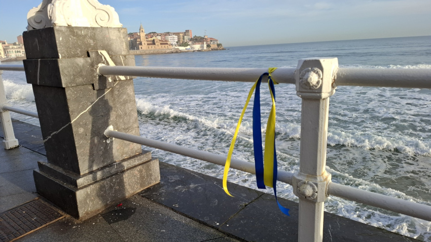 Lazo azul y amarillo (colores de la bandera de Ucrania) en el Muro de San Lorenzo, en Gijón