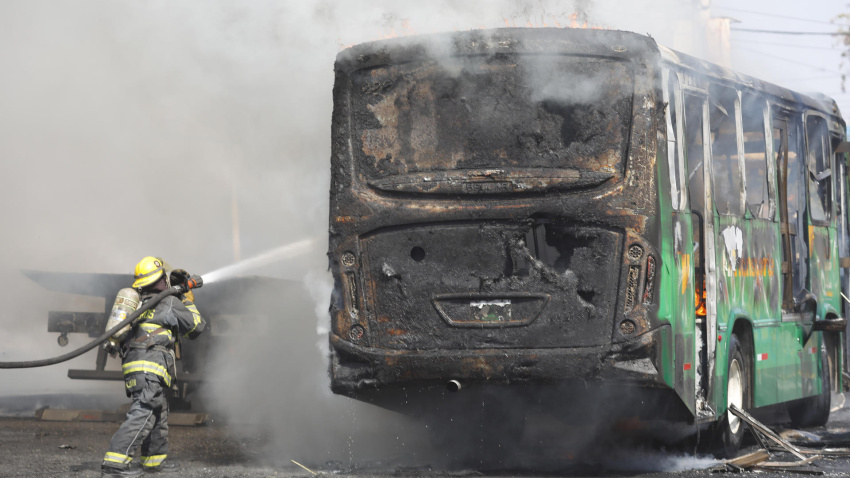 Un integrante del Cuerpo de Bomberos de Guadalajara intenta apagar un vehículo incendiado este domingo, en Guadalajara