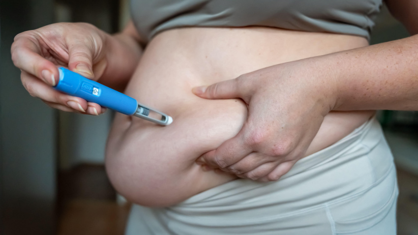 Mujer inyectándose un medicamento GLP-1 para bajar de peso en la grasa abdominal.
