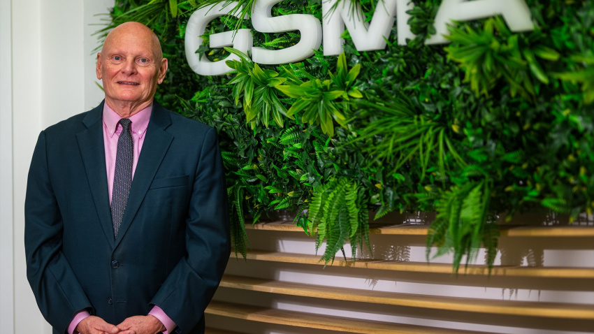 El CEO y director ejecutivo de GSMA Ltd., John Hoffman posando con el logo de la empresa de fondo.