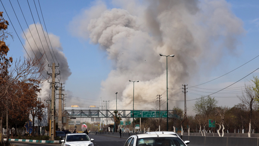 People run for safety as smoke rises after an airstrike in central Tehran, Iran