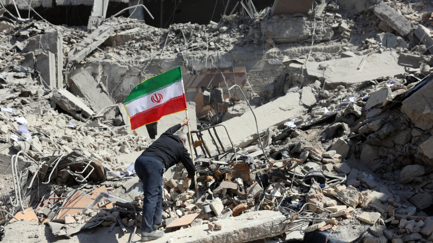 Un hombre iraní coloca la bandera nacional de Irán entre las ruinas de una estación de policía dañada en el centro de Teherán, Irán.