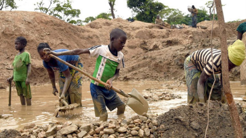 Un niño trabaja en una mina de República Democrática del Congo, sujetando una pala más grande que él mismo