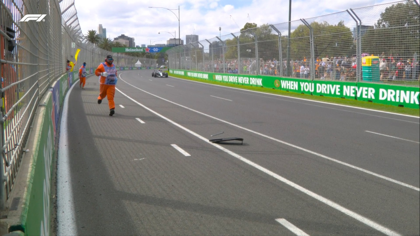 Un comisario entra en la pista para retirar el trozo de pieza de Checo Pérez.