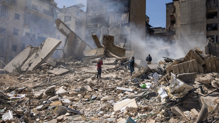 Periodistas informan mientras el humo se eleva desde un edificio residencial arrasado por un ataque israelí en la madrugada en el centro de Beirut, Líbano.