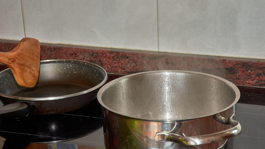 3A1C9R7 A close-up of a grandmother?s hands holding wooden cooking utensils while preparing a meal on a modern stovetop.