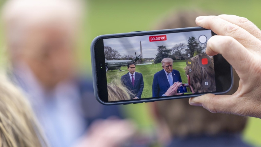 Una persona graba con un teléfono al presidente de Estados Unidos, Donald J. Trump, respondiendo a una pregunta de los medios de comunicación mientras camina para abordar el helicóptero Marine One en el jardín sur de la Casa Blanca en Washington.