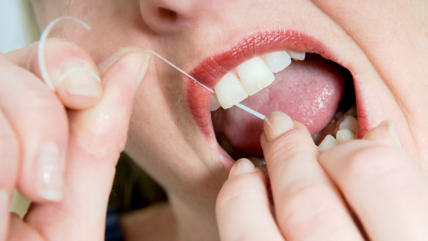 Imagen de recurso de una mujer utilizando hilo dental