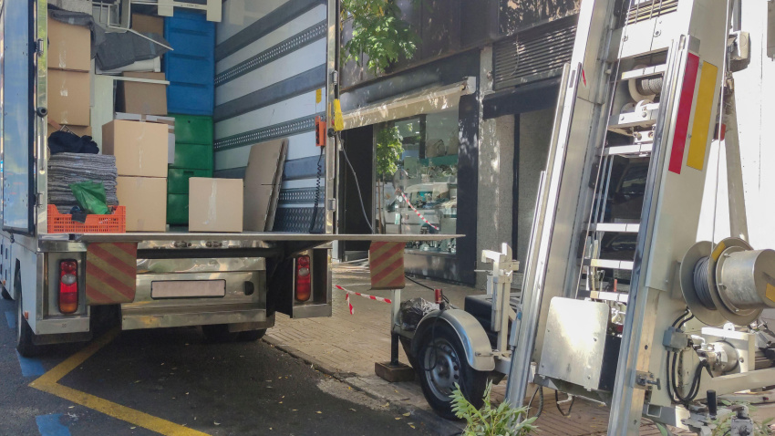 Camión semirremolque de mudanzas y plataforma elevadora en la calle del centro.