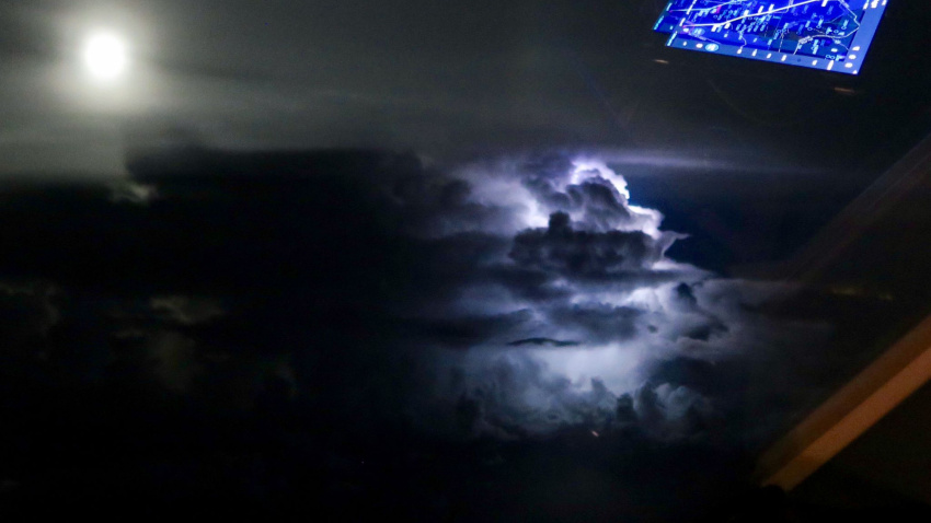 Relámpago entre las nubes mientras un avión sobrevuela una tormenta